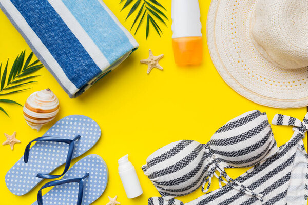 Woman swimwear and beach accessories flat lay top view on colored background Summer travel concept. bikini swimsuit, straw hat and seasheels. Copy space Top view.