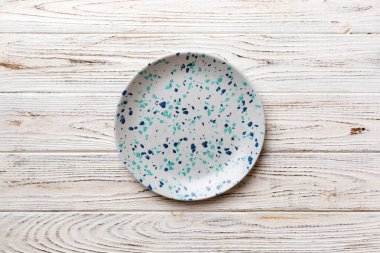 Ahşap zemindeki boş renkli tabağın üst görünümü. Tasarımın için boş boşluk.