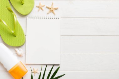 Blank writing book with summer beach accessories on background, copy space. Flat lay with copy space.