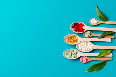 Renkli arka planda tahta kaşıkta vitamin ve mineral haplarının üst görünümü. Muhtelif ilaç haplarının en üst görüntüsü. Beslenme takviyesi sağlık ürünleri.