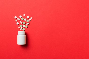Renkli arka planda plastik şişede çok renkli haplar ve kapsüller, kopyalama alanı. Çeşitli ilaç tabletleri ve haplar, vitamin ve besin takviyeleri kavramı.