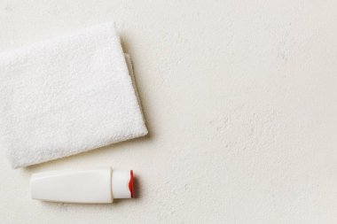 Kozmetik şampuan şişesi renkli bir masada havluyla birlikte. Banyo arka planı, el ve vücut bakımı için tuvalet aksesuarları..