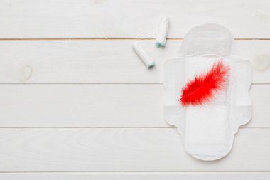 Kadın pedleri ve tamponları. Pembe ve menekşe arka planda izole edilmiş bir arka planda hijyenik pedlerin yanında uzanıyor. Kadın hijyeni ve adet dönemi konsepti.