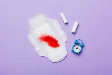 Alarm saatini hijyenik kadın tamponları ve regl pedleri ile çalıyor. Tıbbi konsept kadın kritik günler ve regl dönemi. Kadın günlük hijyen. Boşluğu kopyala.