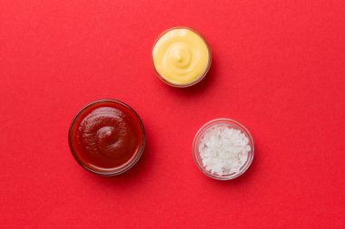 Renkli arkaplanda bir kase tuz, ketçap ve peynir sosu, fotokopi alanı ile üst manzara.