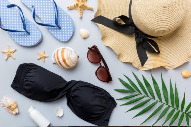 Kadın mayo ve plaj aksesuarları renkli arka plan yaz seyahati konseptine düz bir görünüm kazandırıyordu. Bikini mayo, hasır şapka ve deniz topuklu ayakkabı. Üst görünümü kopyala.