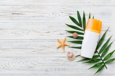 Güneş kremi şişesi. Güneş korumalı krem ve tropik yeşil yapraklı deniz kabukları olan bir şişe..