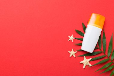 Güneş kremi şişesi. Güneş korumalı krem ve tropik yeşil yapraklı deniz kabukları olan bir şişe..