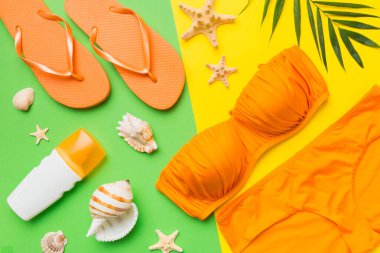 Kadın mayo ve plaj aksesuarları renkli arka plan yaz seyahati konseptine düz bir görünüm kazandırıyordu. Bikini mayo, hasır şapka ve deniz topuklu ayakkabı. Üst görünümü kopyala.