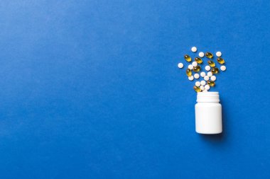 Renkli arka planda plastik şişede çok renkli haplar ve kapsüller, kopyalama alanı. Çeşitli ilaç tabletleri ve haplar, vitamin ve besin takviyeleri kavramı.