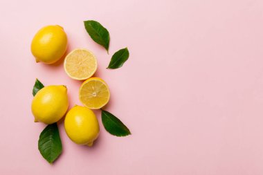 Renkli arka planda yeşil yapraklı taze limonlar, üst görünüm, metin için boşluk.