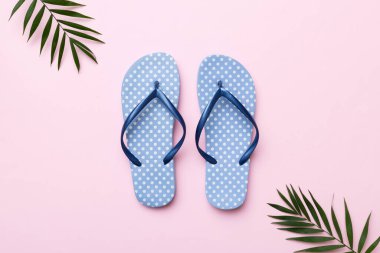 Renkli arka planda parmak arası terlikleri ve deniz kabuğu olan düz bir kompozisyon. Metin üstü görünümü için boşluk.