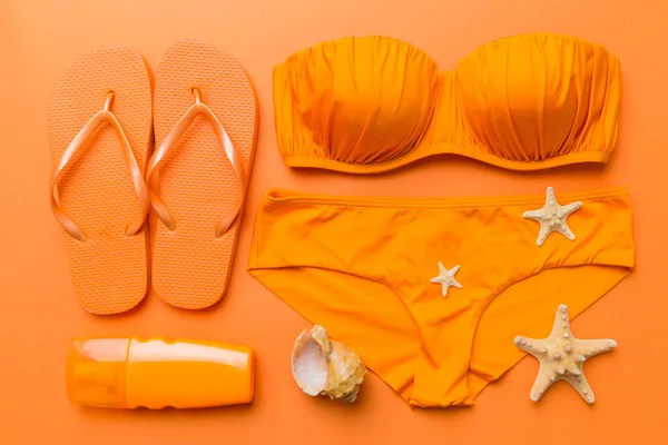 Woman swimwear and beach accessories flat lay top view on colored background Summer travel concept. bikini swimsuit, straw hat and seasheels. Copy space Top view.