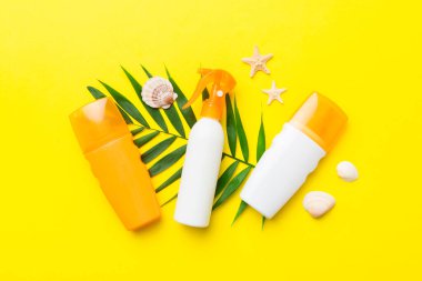 Güneş kremi şişesi. Güneş korumalı krem ve tropik yeşil yapraklı deniz kabukları olan bir şişe..