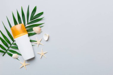 Güneş kremi şişesi. Güneş korumalı krem ve tropik yeşil yapraklı deniz kabukları olan bir şişe..