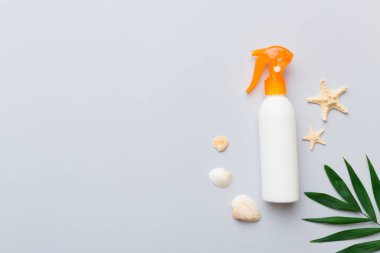 Güneş kremi şişesi. Güneş korumalı krem ve tropik yeşil yapraklı deniz kabukları olan bir şişe..