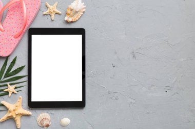 Renkli arka planda tablet ve plaj aksesuarlarıyla düz kompozisyon. Boş ekran ile tablet bilgisayarı kopyalama alanı ile maket.