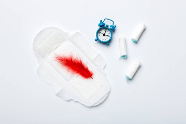 Alarm saatini hijyenik kadın tamponları ve regl pedleri ile çalıyor. Tıbbi konsept kadın kritik günler ve regl dönemi. Kadın günlük hijyen. Boşluğu kopyala.