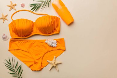 Woman swimwear and beach accessories flat lay top view on colored background Summer travel concept. bikini swimsuit, straw hat and seasheels. Copy space Top view.