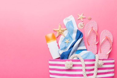 Plaj aksesuarları renkli arka plan yaz seyahati konseptinde düz bir görünüm sergiliyordu. İçinde deniz yıldızı ve deniz kabuğu olan bir çanta. Üst görünüm.