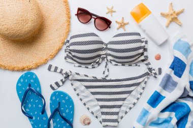 Kadın mayo ve plaj aksesuarları renkli arka plan yaz seyahati konseptine düz bir görünüm kazandırıyordu. Bikini mayo, hasır şapka ve deniz topuklu ayakkabı. Üst görünümü kopyala.