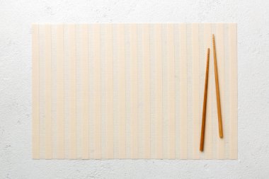 Çimento arka planında iki çubuk ve bambu paspas. Üst görünüm, alanı kopyala.