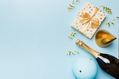 Renkli arka planda şampanya şişesi hediye paketi kurdeleleri ve konfetilerin düz kompozisyonu vardı. Düz konum, üst görünüm tatil konsepti.