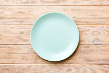 Ahşap zemindeki boş mavi tabağın üst görüntüsü. Tasarımın için boş boşluk.
