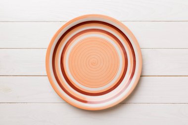 Ahşap arka planda boş turuncu tabağın üst görüntüsü. Tasarımın için boş boşluk.