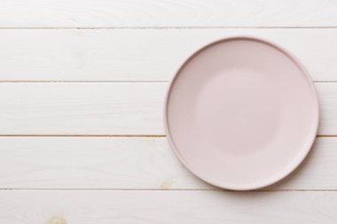 Ahşap arka planda boş pembe tabağın üst görüntüsü. Tasarımın için boş boşluk.