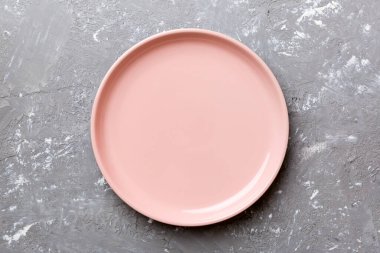 Çimento arka planındaki boş pembe tabağın üst görüntüsü. Tasarımın için boş boşluk.
