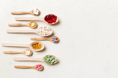 Renkli arka planda tahta kaşıkta vitamin ve mineral haplarının üst görünümü. Muhtelif ilaç haplarının en üst görüntüsü. Beslenme takviyesi sağlık ürünleri.