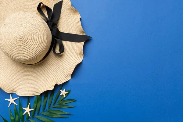 Summer holidays. Summer concept with straw hat and tropical leaf. Flat lay, top view, copy space.