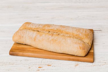 Tahtanın üzerinde beyaz ahşap zemine karşı taze pişmiş ekmek. Ekmeği kopyalama alanı ile perspektif görünümü.