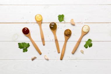 Masa arkaplanındaki kaşıklarda farklı soslar, düz üst görünüm.