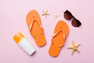 Yaz yolculuğu konsepti. Parmak arası terlikler, güneş gözlükleri ve beyaz üzerine deniz yıldızı. Renkli arkaplanda üst görünüm.
