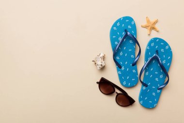 Yaz yolculuğu konsepti. Parmak arası terlikler, güneş gözlükleri ve beyaz üzerine deniz yıldızı. Renkli arkaplanda üst görünüm.