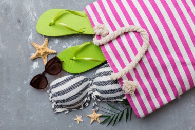 Kadın mayo ve plaj aksesuarları renkli arka plan yaz seyahati konseptine düz bir görünüm kazandırıyordu. Bikini mayo, hasır şapka ve deniz topuklu ayakkabı. Üst görünümü kopyala.