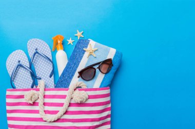 Plaj aksesuarları renkli arka plan yaz seyahati konseptinde düz bir görünüm sergiliyordu. İçinde deniz yıldızı ve deniz kabuğu olan bir çanta. Üst görünüm.
