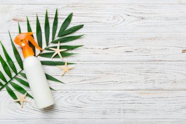 Güneş kremi şişesi. Güneş korumalı krem ve tropik yeşil yapraklı deniz kabukları olan bir şişe..