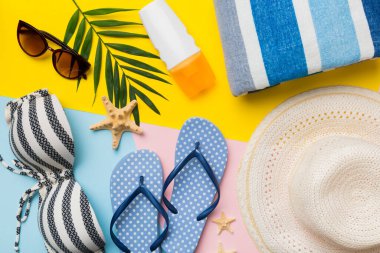 Kadın mayo ve plaj aksesuarları renkli arka plan yaz seyahati konseptine düz bir görünüm kazandırıyordu. Bikini mayo, hasır şapka ve deniz topuklu ayakkabı. Üst görünümü kopyala.