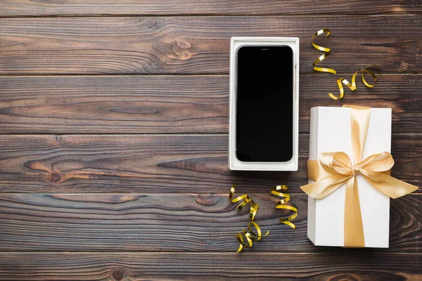 Opened gift box with gold ribbon and smartphone on color background, top view. Blank open box packaging mockup , Template for your design - branding mockup.