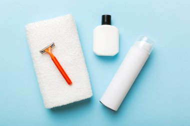 Tıraş Adam seti. Traş makinesi, havlu, losyon ve renkli arka planda tıraş köpüğü. Erkekler banyo aksesuarları üst görünüm.