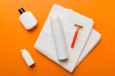 Tıraş Adam seti. Traş makinesi, havlu, losyon ve renkli arka planda tıraş köpüğü. Erkekler banyo aksesuarları üst görünüm.