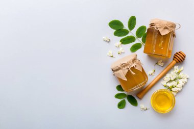 Akasya çiçekli ve yapraklı bal kavanozu. Taze bal üst görünüm düz yatıyordu.