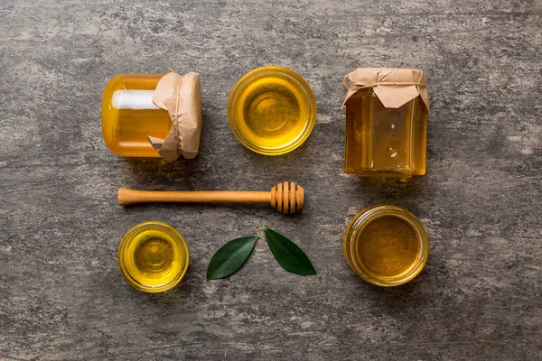 Honey jar with wooden honey dipper on white background top view with copy space. Delicious honey bottle.