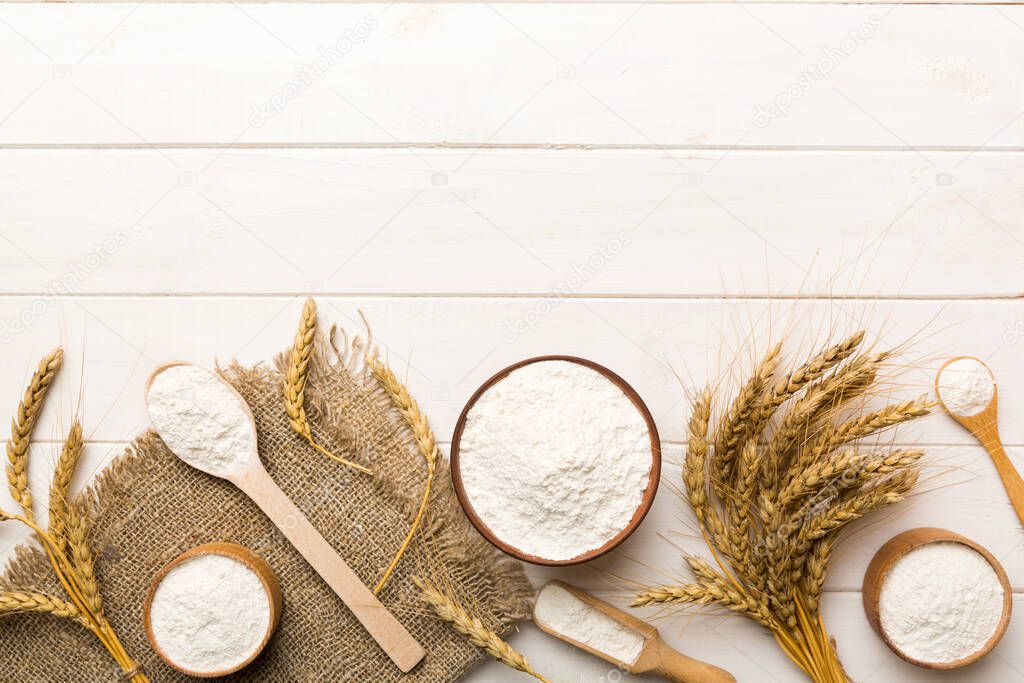 Flat lay of Wheat flour in wooden bowl with wheat spikelets on colored background. world wheat crisis.