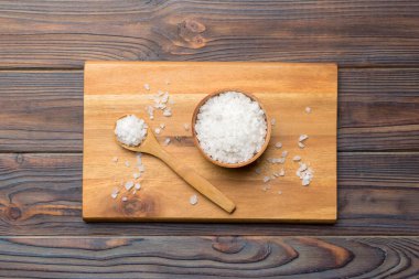 Ahşap bir arka planda ahşap bir kase tuz kristali. Kırsal kaselerdeki tuz, fotokopi alanı olan üst görünüm.