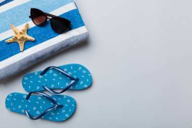 Yaz yolculuğu konsepti. Parmak arası terlikler, güneş gözlükleri ve beyaz üzerine deniz yıldızı. Renkli arkaplanda üst görünüm.
