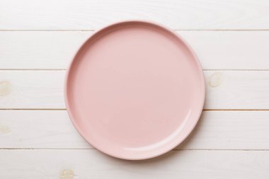 Ahşap arka planda boş pembe tabağın üst görüntüsü. Tasarımın için boş boşluk.